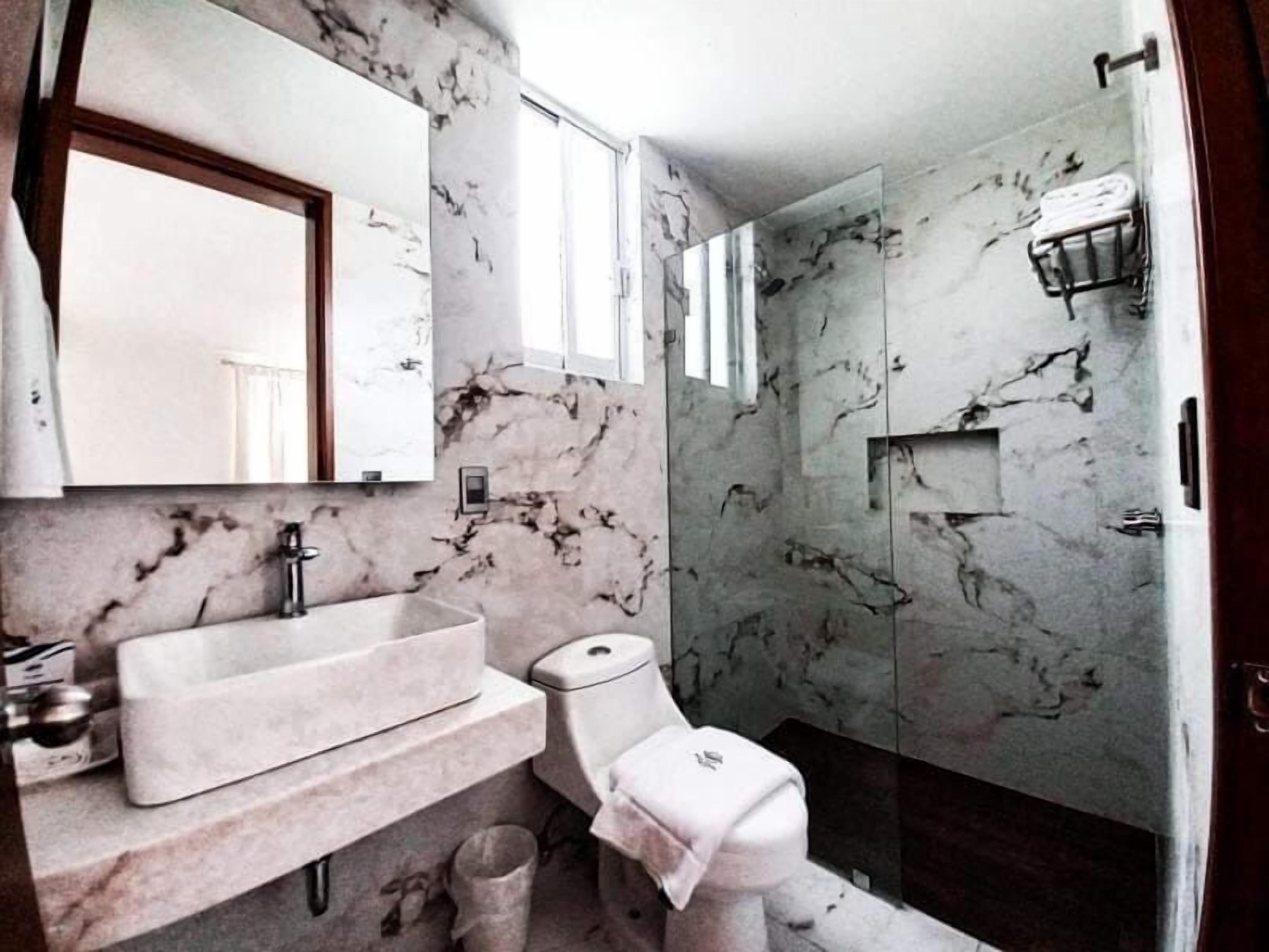 Un bagno con un lavabo in marmo, un water e un box doccia in vetro.