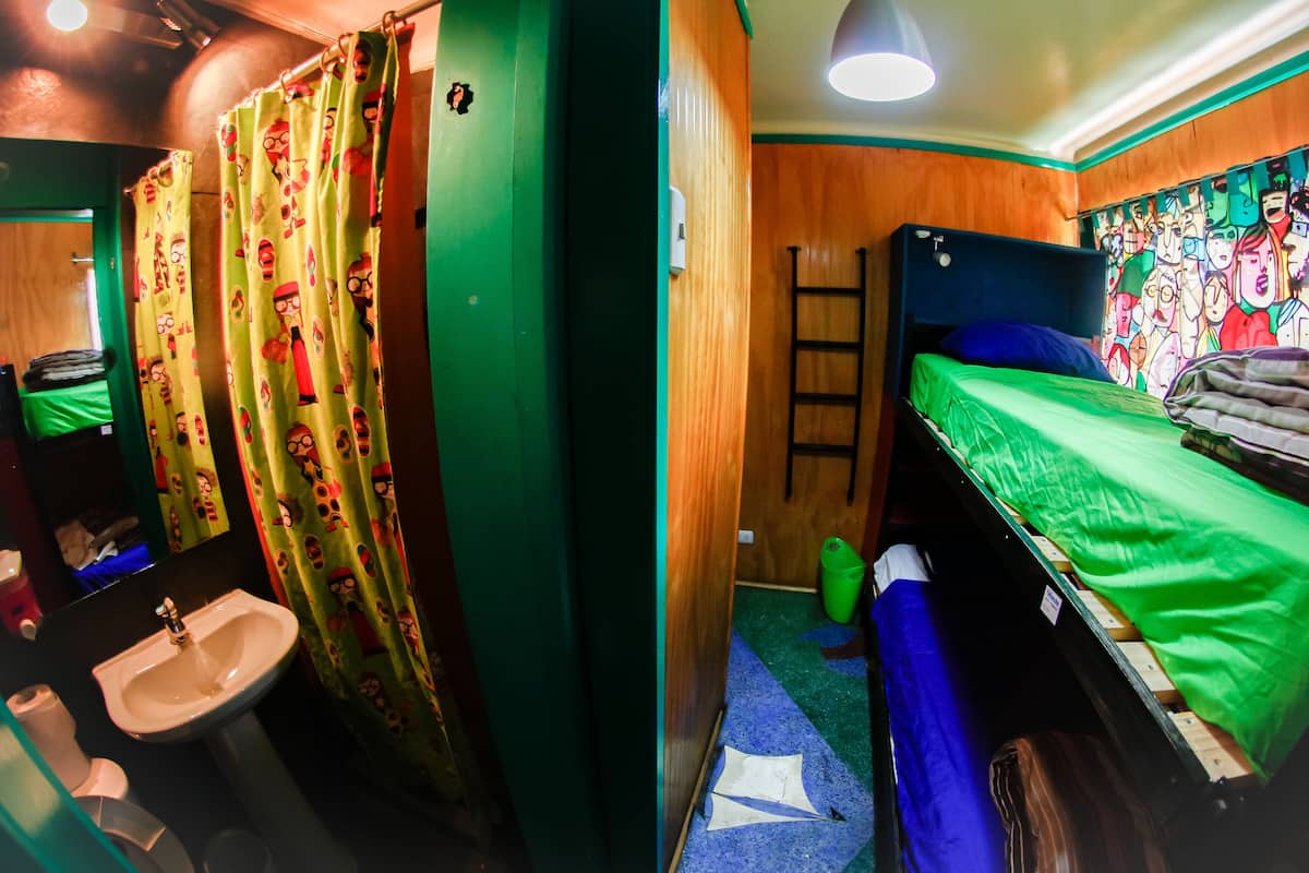 Une petite pièce compacte comprenant un lit superposé, un lit simple, un lavabo et un espace douche.