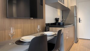 Une cuisine moderne équipée d’un téléviseur à écran plat, d’un réfrigérateur et d’un coin repas avec une table mise pour deux personnes.