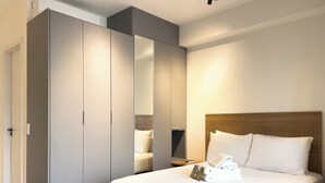 Une chambre moderne avec un grand lit, une armoire et un miroir.
