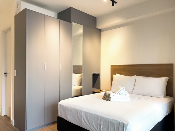 A modern bedroom with a large bed, a wardrobe, and a mirror.