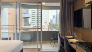 Une chambre d’hôtel avec un balcon, un coin repas comprenant une table et des chaises, et un téléviseur fixé au mur.