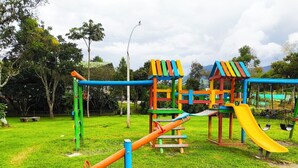 Un parque infantil con tobogán, estructuras de escalada y columpios.