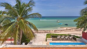 Une vue sur la plage, avec des palmiers, une piscine et un ciel dégagé.