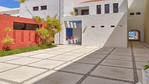 Un bâtiment moderne avec une partie en briques rouges, une façade en stuc blanc et une terrasse carrelée.