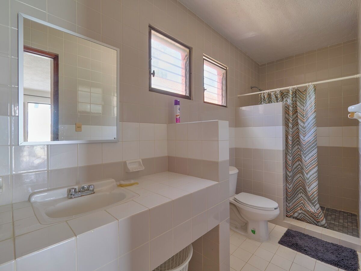 A bathroom with a sink, toilet, and shower area.