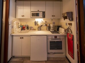 Eine kompakte Küche mit Mikrowelle, Backofen und Geschirrspüler.