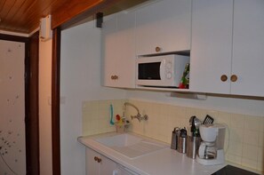 A kitchen with white cabinets, a microwave, a coffee maker, and a sink with a faucet.