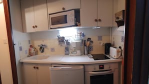 Kompakti keittiö, jossa on mikroaaltouuni, leivänpaahdin ja uuni.