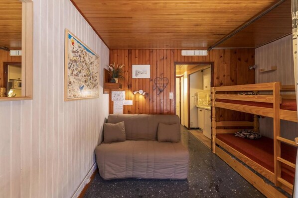 A cozy room with a wooden bunk bed, a cushioned bench, and a sofa.