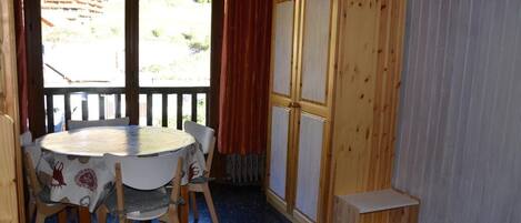 A room with a round table, four chairs, a wooden cabinet, and a view through a door.
