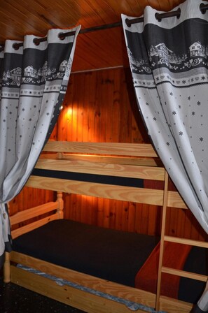 A bunk bed with a wooden headboard and footboard, a black mattress, and a wooden ladder.