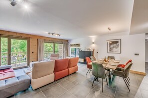 A spacious living area with a sofa, dining table, and chairs. There is a balcony with a view of greenery. - 2nd floor, view mountain, balcony, tv, ski locker, 102m², Champagny-en-Vanoise (Champagny-en-Vanoise)