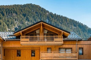A wooden chalet with a balcony, large windows, and a mountain backdrop. - 2nd floor, view mountain, balcony, tv, ski locker, 102m², Champagny-en-Vanoise (Champagny-en-Vanoise)