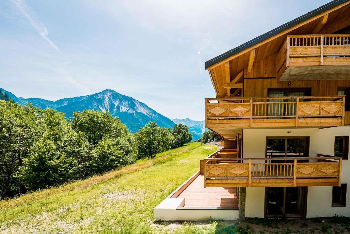 Un bâtiment en bois à deux étages, doté de balcons, qui se dresse sur un fond de paysage montagneux.
