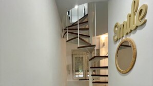 A narrow hallway with a spiral staircase, a mirror, and a 'smile' sign on the wall. - Precioso Apartamento Cerca de Marbella con Vistas y Playa (Mijas)