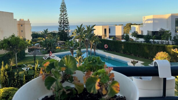 A view of a modern building with a pool, surrounded by greenery and a clear sky. - Precioso Apartamento Cerca de Marbella con Vistas y Playa (Mijas)