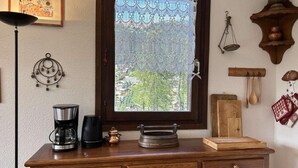 Un aparador de madera con una cafetera, un hervidor y una bandeja.