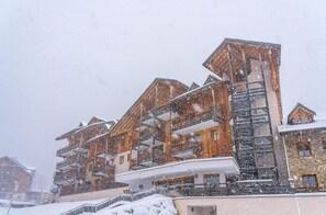 Un hôtel à plusieurs étages, doté de balcons, et depuis lequel on peut voir un télésiège.