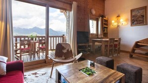Ein gemütliches Wohnzimmer mit Holzausstattung, einem Essbereich und einem Balkon mit Bergblick.