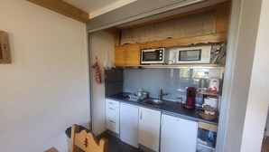 Une cuisine de taille réduite avec des meubles blancs, un plan de travail noir et un four à micro-ondes.