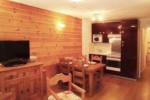 A compact living space with a wooden interior, a dining area, a kitchenette, and a television. - 5th floor, view forest, balcony, tv, 43m², Les Orres (Les Orres)