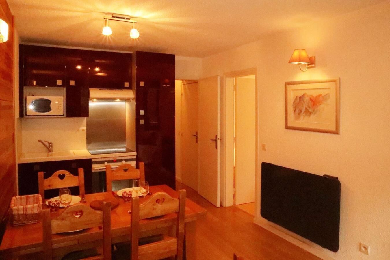 A compact kitchen with a microwave, stove, and dining table with chairs.