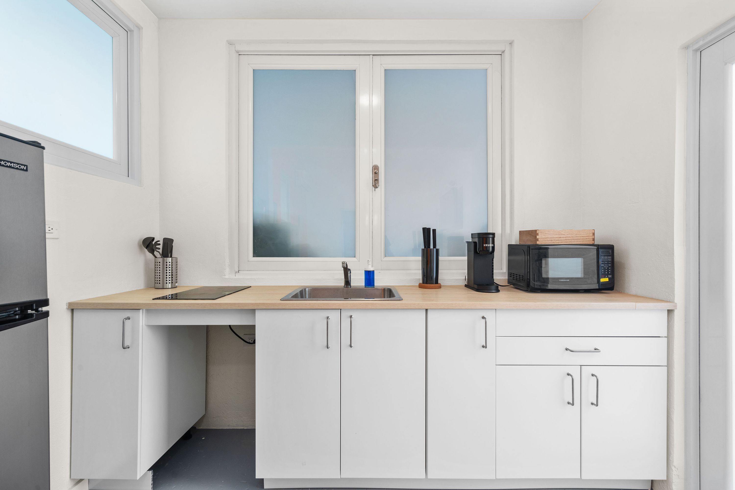 A compact kitchen with a window, a microwave, a coffee maker, and a sink.