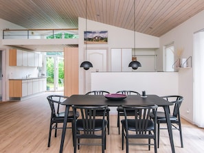 Zona pranzo moderna con un tavolo grande e sedie, una cucina sullo sfondo e vista sull'esterno.