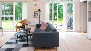 A spacious living room with a grey sofa, a black coffee table, and a large window overlooking a garden. - 4 Star Holiday Home in Tarm (Tarm)