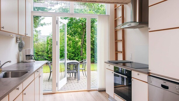 A modern kitchen with a large sliding glass door leading to an outdoor patio. - 4 Star Holiday Home in Tarm (Tarm)