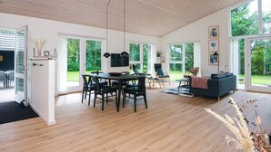 A spacious living area with a dining table, chairs, a sofa, and a large window offering a view of the outdoors. - 4 Star Holiday Home in Tarm (Tarm)