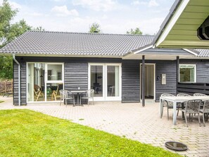 A modern house with a patio area, a dining table, and chairs.