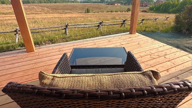 A covered outdoor seating area with a table and wicker chairs, overlooking a field and distant mountains. - Adventure Basecamp Fly Fishing Modern Alpine Home Near Jackson “Superfly” Cabin (Alpine)
