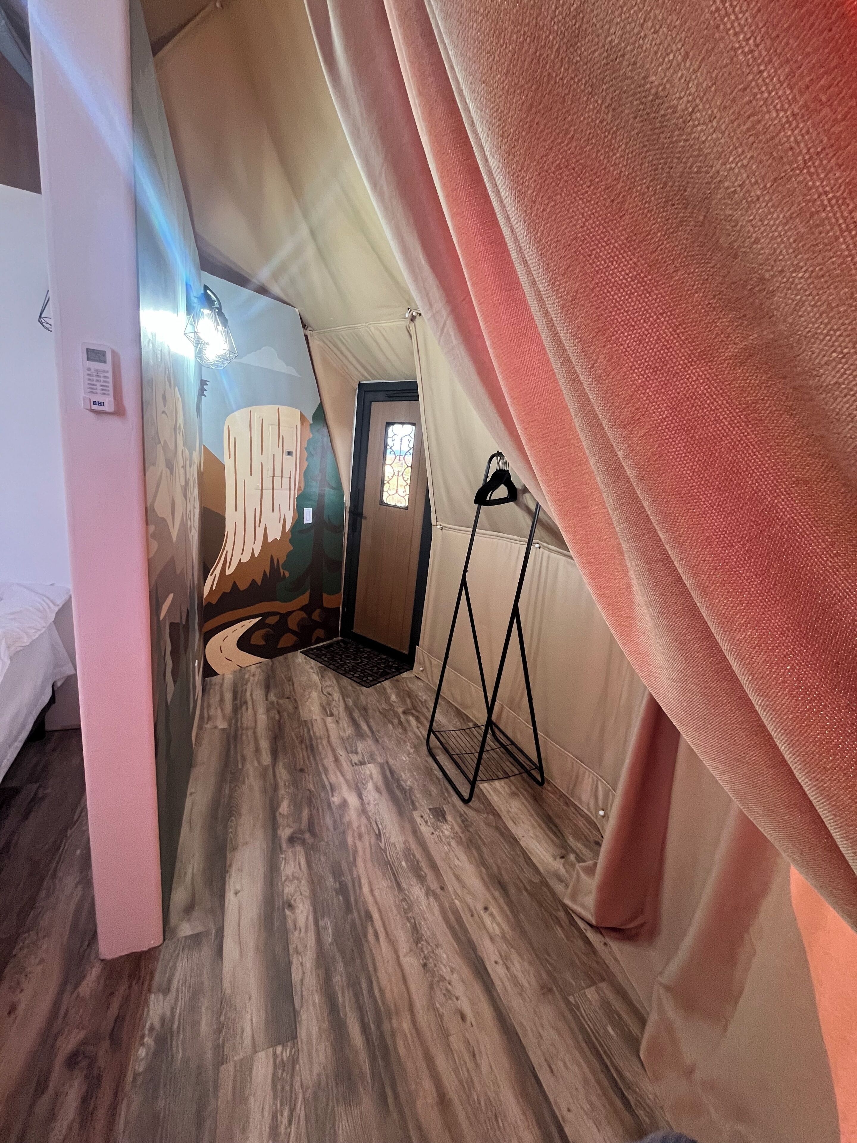 A tented room with a bed, a hanging light fixture, and a door with a stained glass window.