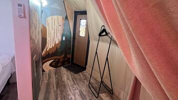 A tented room with a bed, a hanging light fixture, and a door with a stained glass window.
