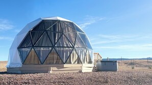 A geodesic dome structure with a transparent window and a smaller adjacent building. - WYnDome - Glamping Dome in Beulah, WY (Beulah)