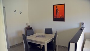 A dining area with a table and chairs, a framed picture on the wall, and a speaker on a stand.