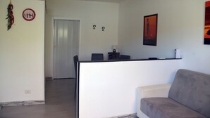A modern living room with a grey sofa, a white partition, and a door leading to another room.