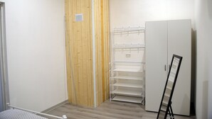 A room with a wooden wardrobe, a white shelving unit, and a white cabinet.