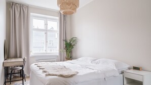 A bedroom with a bed, a desk, a chair, a potted plant, and a window with curtains. - Modern Top-Floor Apt. in Helsinki (Helsinki)