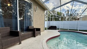 A covered outdoor swimming pool area with wicker furniture and a pergola. - Spacious House w/ Heated Pool & Hot Tub near Tampa (Brandon)