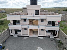 A multi-story building with a central staircase, balconies, and a large water tank on the roof.