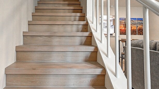 A staircase with wooden steps and white railings leading to a landing with a door. - Stylish Old Town 2Bd 2Ba Townhome Pool Parking AC Fashion Square (Scottsdale)
