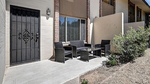 An outdoor patio with wicker furniture, a black gate, and a brick wall. - Stylish Old Town 2Bd 2Ba Townhome Pool Parking AC Fashion Square (Scottsdale)
