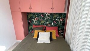 Et soveværelse med en seng, pink skabe og en blomstret sengegavl.