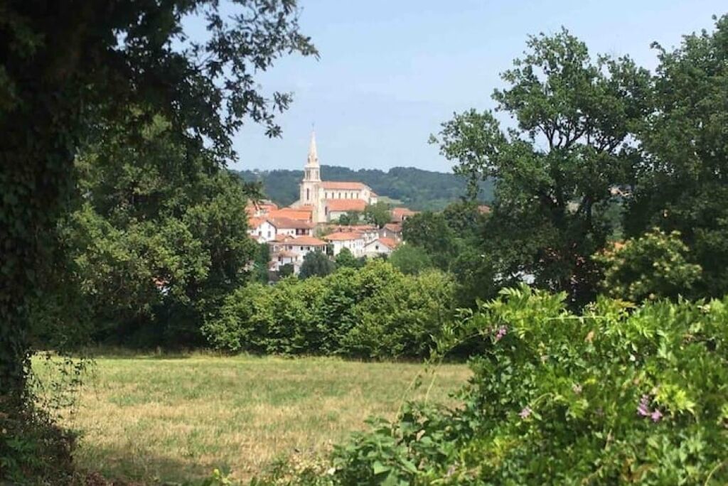 A historic building with a prominent tower, surrounded by lush greenery and trees.
