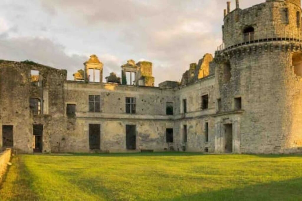 Un edificio histórico de piedra con un patio central, que cuenta con una torre y numerosas ventanas.