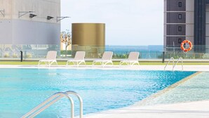 Une piscine avec des chaises longues blanches et une bouée de sauvetage.