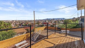A rooftop terrace with a wooden deck, metal railing, and a view of a cityscape. - Cozy 1B Private Terrace View (El Paso)